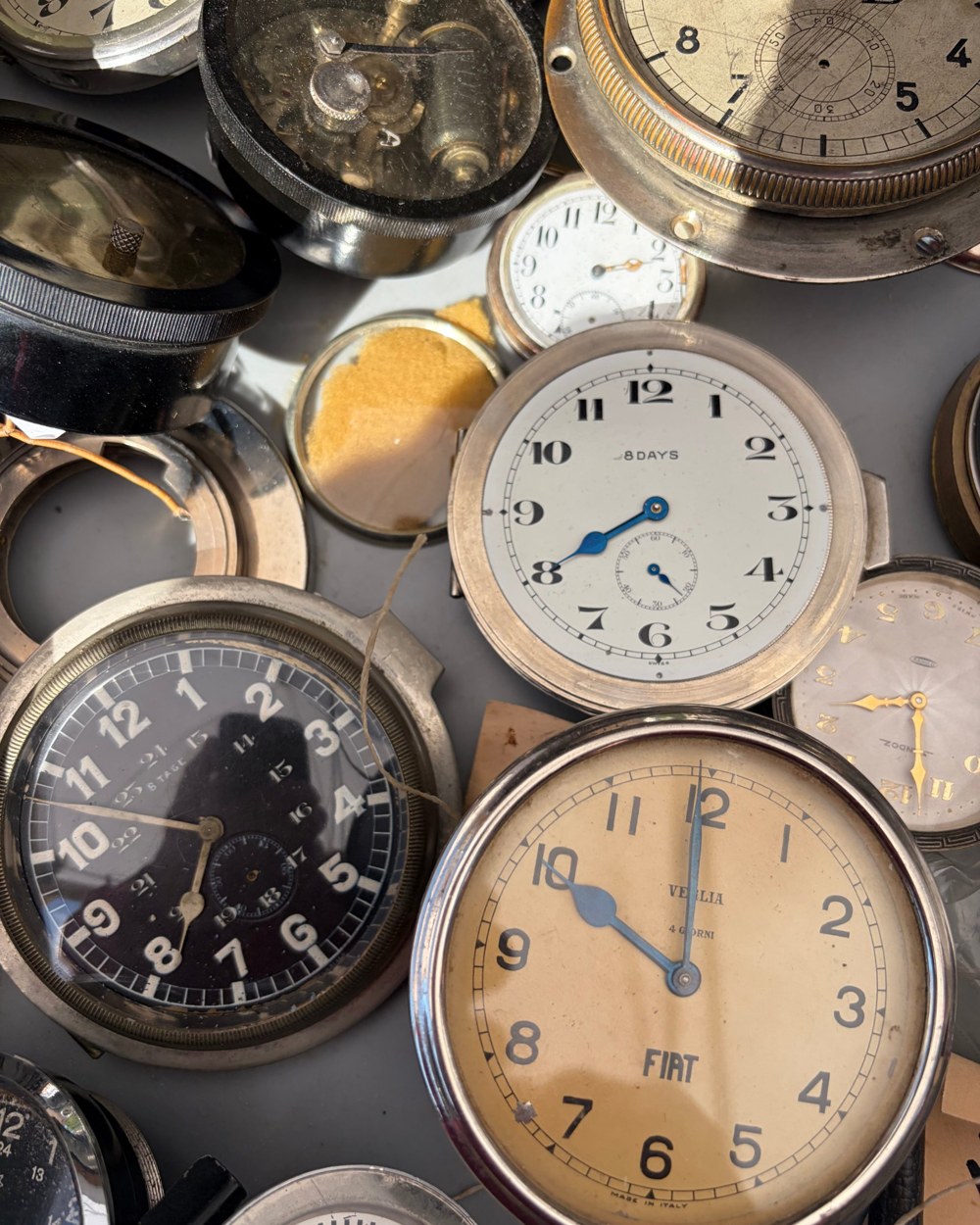 A tray of old clock faces and pocket watch dials