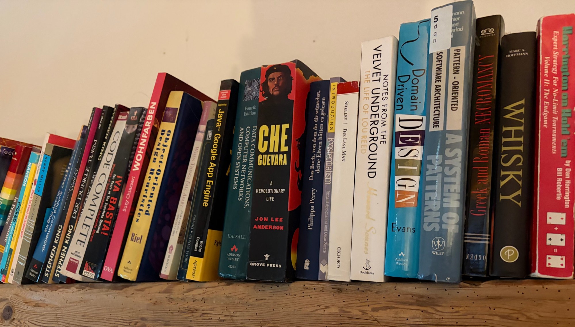 A shelf of well-read books on a rough wooden beam